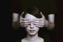 Une personne place ses mains devant les yeux d'une jeune-femme